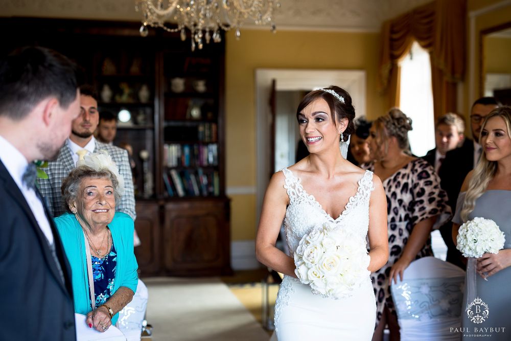 Intimate wedding ceremony moment in an elegant room with chandelier and bookshelves.