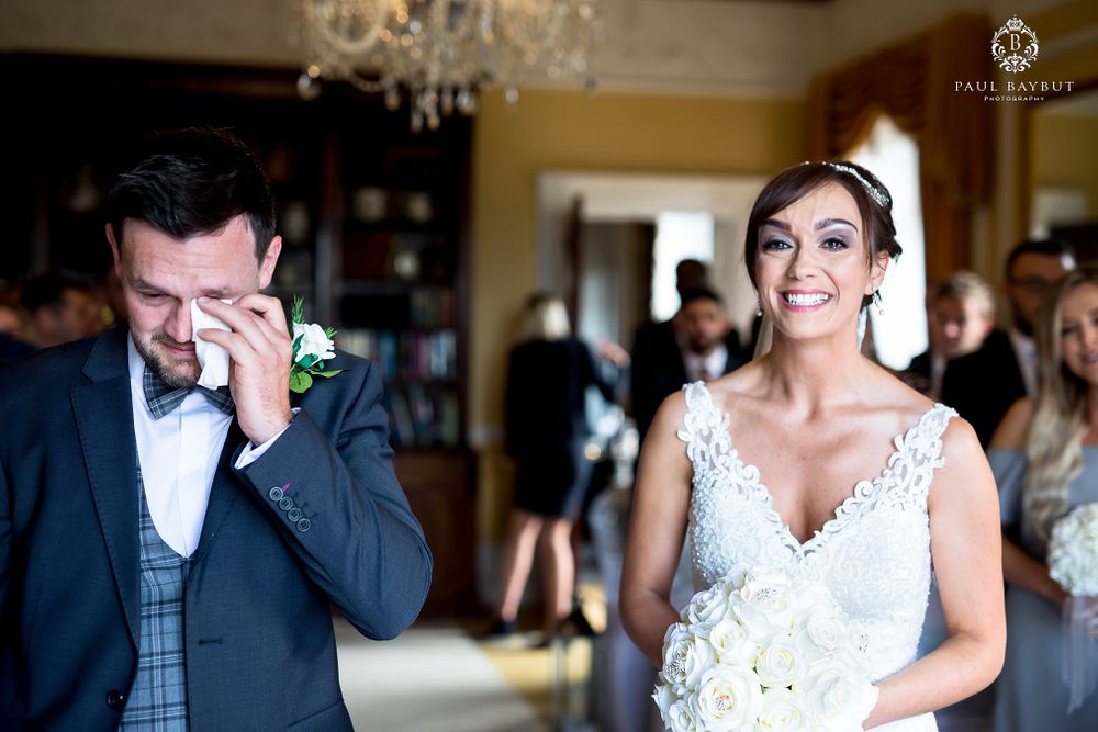 Wedding ceremony filled with emotion in an elegant indoor venue with chandelier.