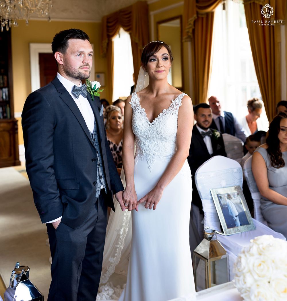 Elegant indoor wedding ceremony with couple standing before guests in formal attire.