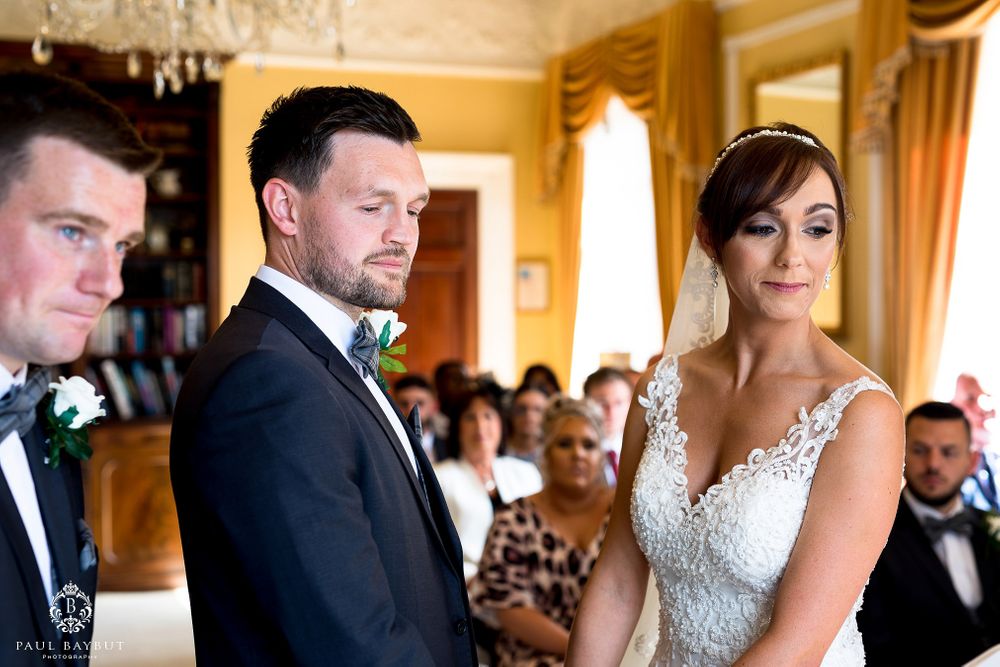 Wedding ceremony in progress in elegant room with yellow walls and crystal chandelier.