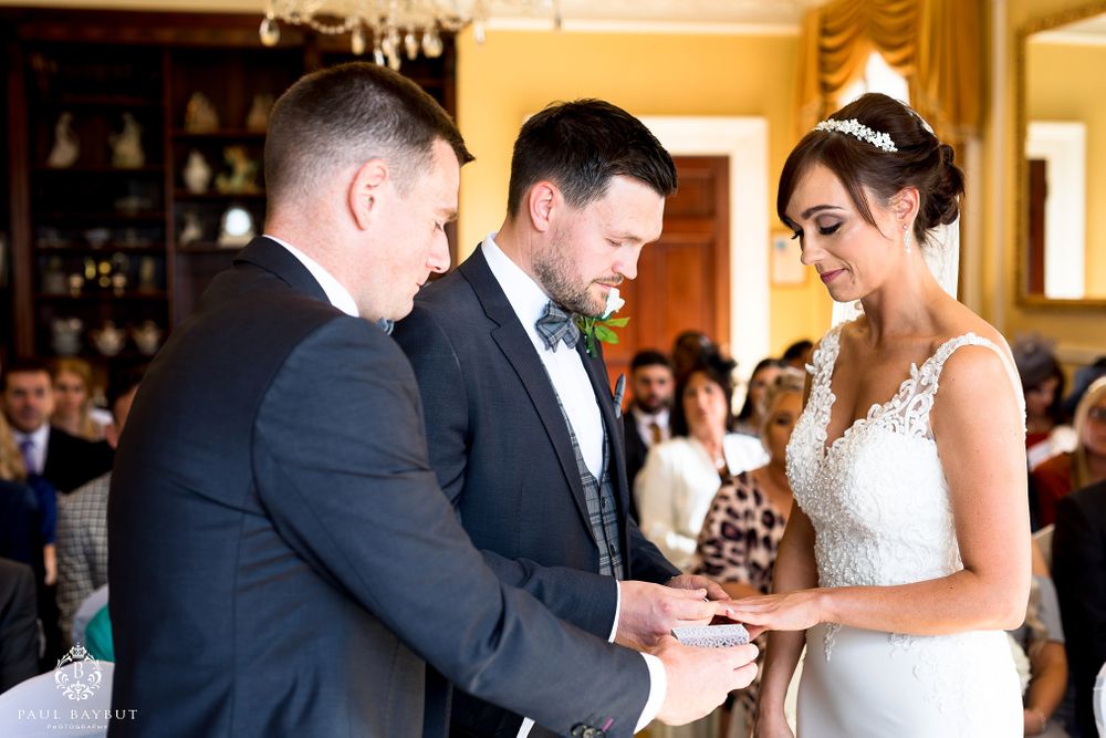 Exchange of rings during wedding ceremony in elegant indoor venue.