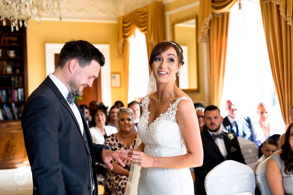 Joyful wedding ceremony moment in elegant yellow room with chandelier and white chairs.
