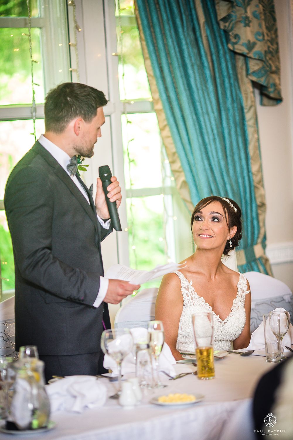 Wedding speech moment captured during reception with couple at head table.