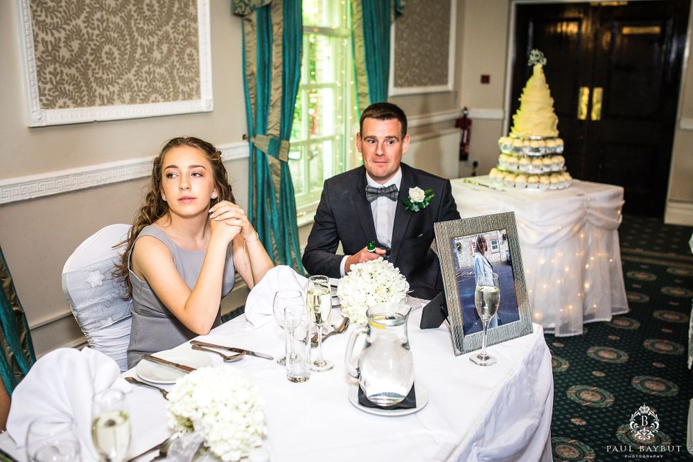 Elegant wedding reception table with classic decor and white tiered cake in the background.
