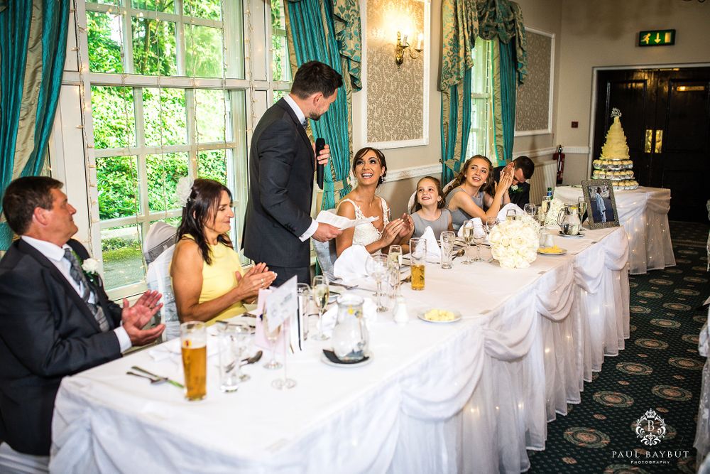 Wedding reception candid moment during speeches at head table with teal decor.