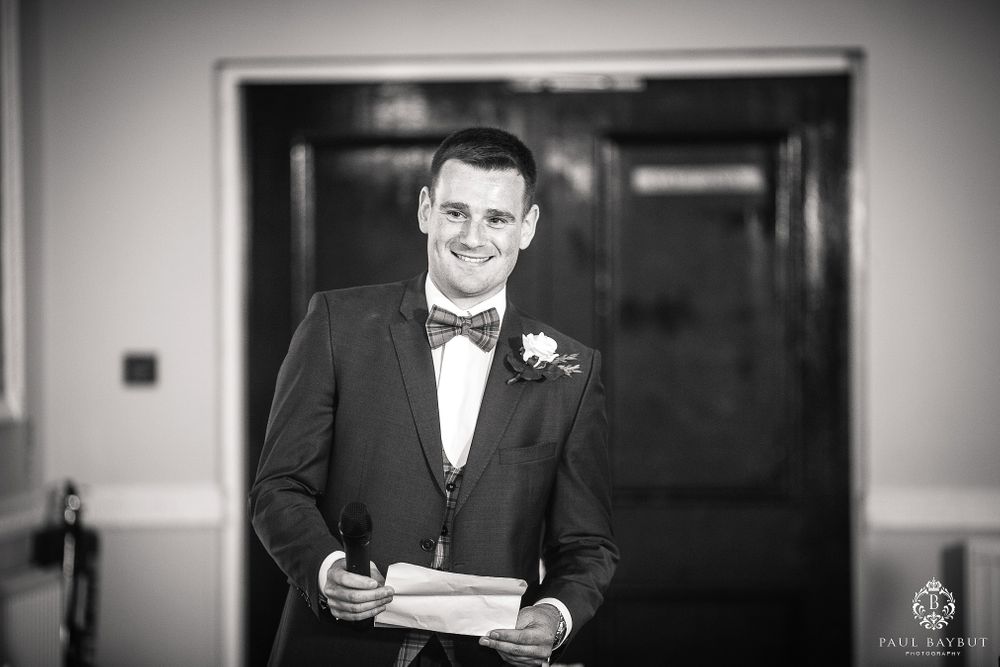 Classic black and white portrait of groom holding speech notes.
