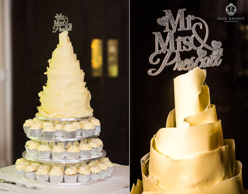 Elegant white tiered wedding cake with Mr and Mrs topper illuminated by soft lighting.