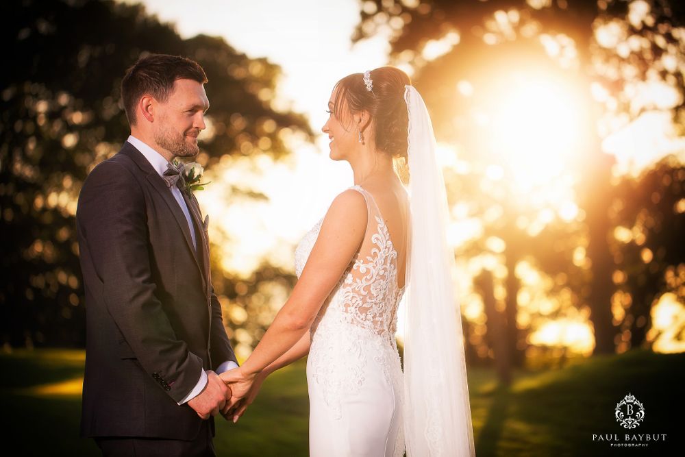 Romantic sunset wedding portrait with golden sunlight filtering through trees.