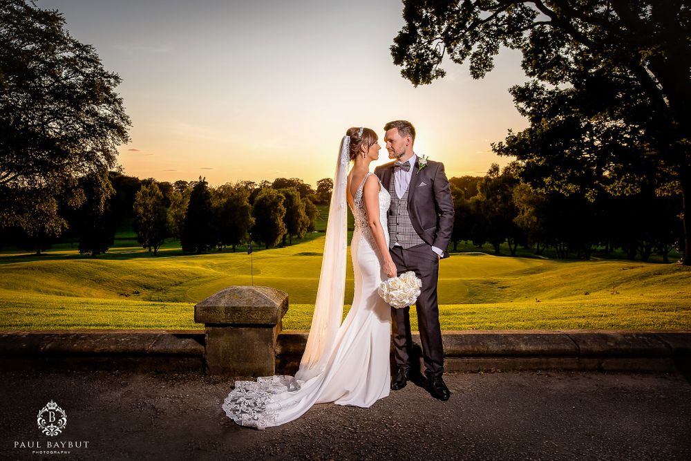 Newlyweds share intimate moment at sunset on manicured golf course grounds.