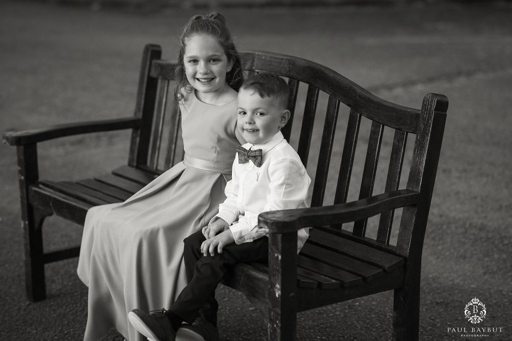 Black and white portrait of two young attendees in formal wear seated on a bench.