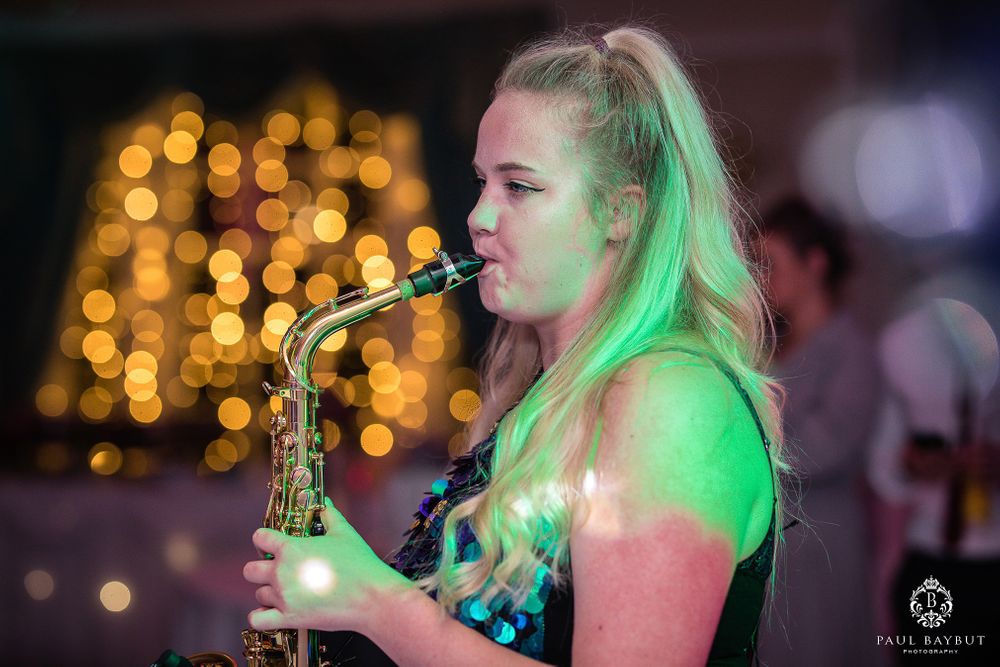 Musician performing with saxophone under green stage lighting at an event.