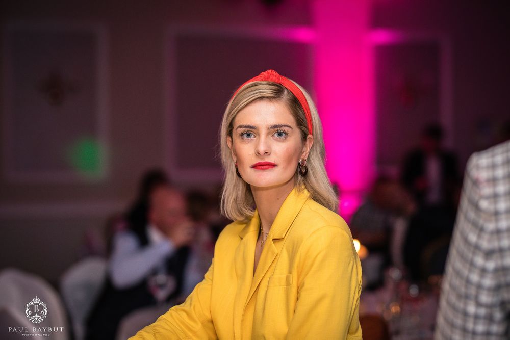 Portrait of guest in yellow blazer with pink lighting in background at formal event.