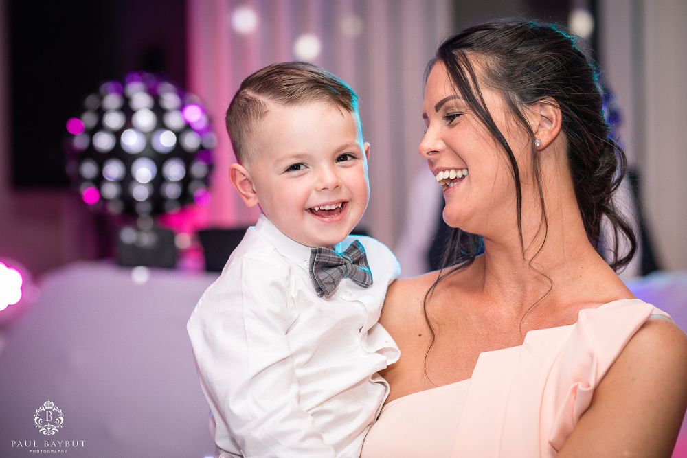 A joyful moment at a wedding reception with pink and purple lighting and a disco ball in the background.