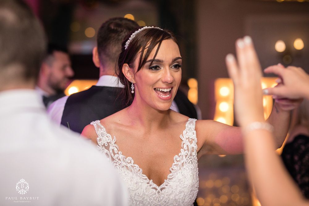 Wedding celebration with bride in lace dress dancing and smiling during reception.