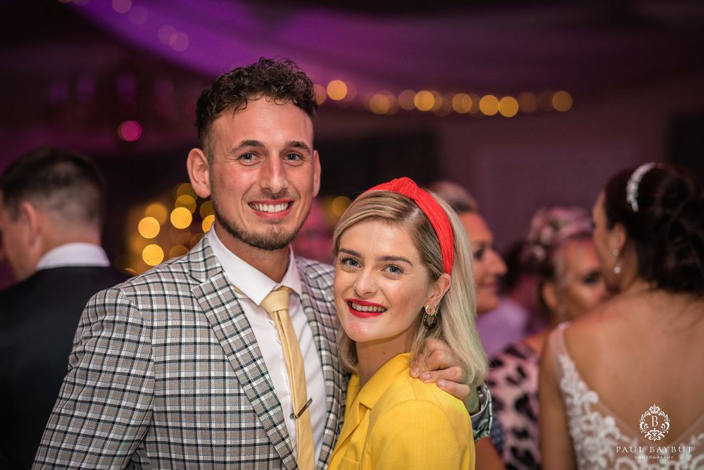 Guests enjoying a wedding reception under purple lighting with festive decorations.