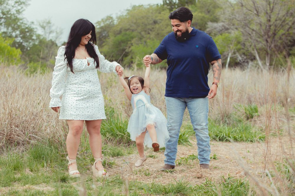 A casual outdoor family portrait session in a natural setting with tall grass.