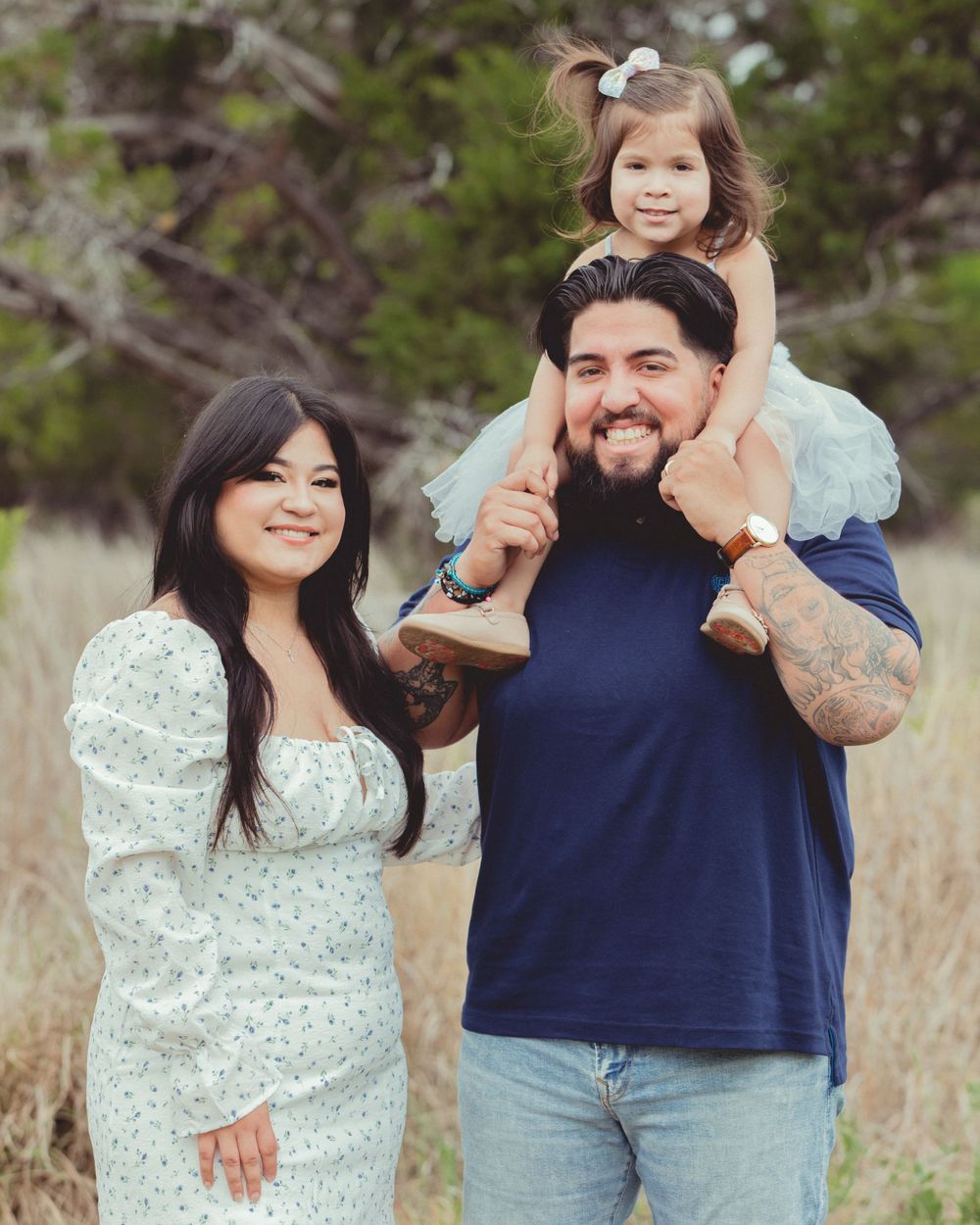 Candid family moments captured in a field with tall grass and trees.