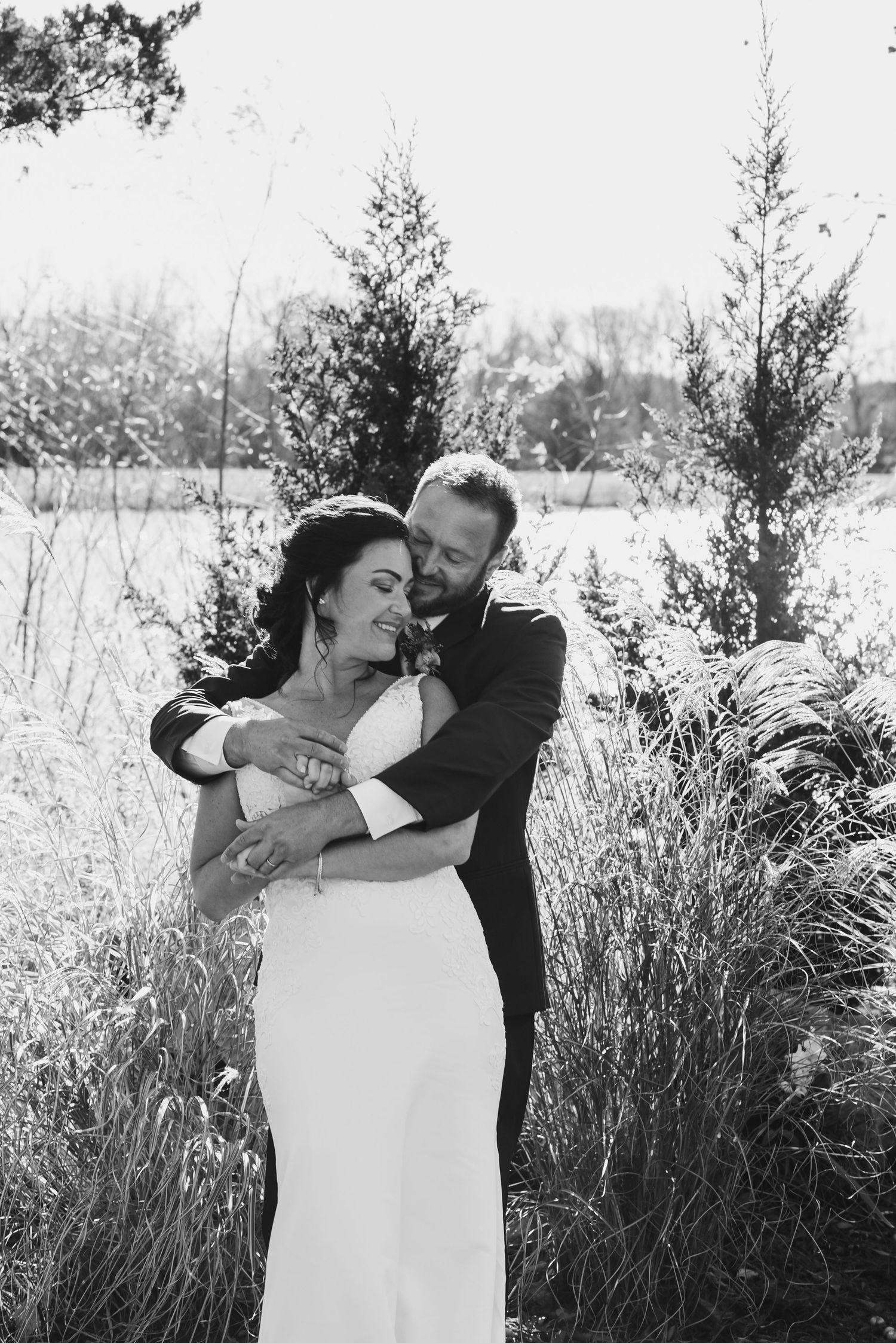 Black and white romantic wedding photos showing a couple embracing outdoors.