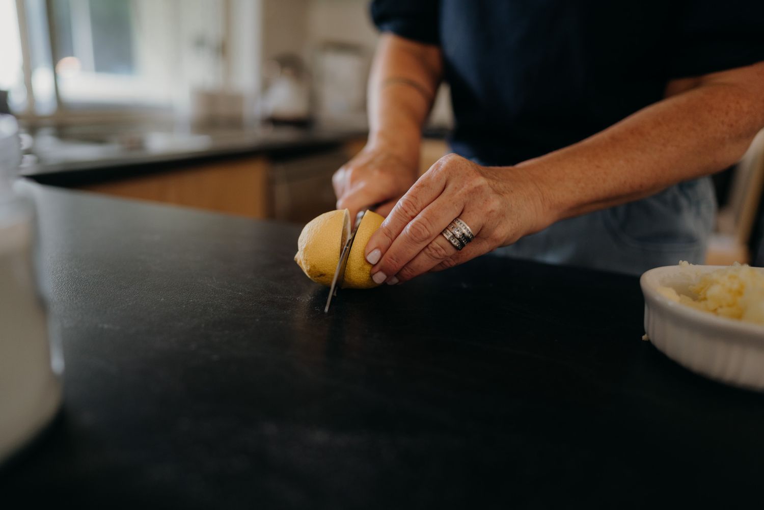 woman cutting a lemon in half on the bench