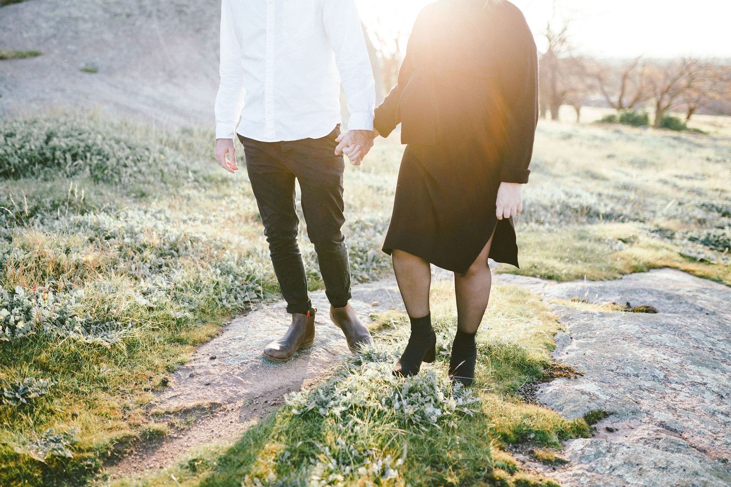 Couple walking together on rocky ground during sunset.