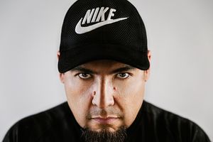 Close-up portrait of someone wearing a black Nike cap against white background.