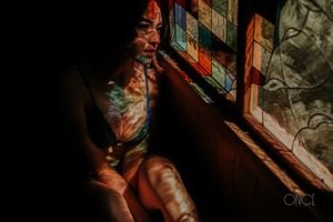 Artistic shadows and lighting on figure through window creating dramatic atmosphere.