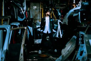 Silhouette figure standing amidst industrial equipment in dark environment.