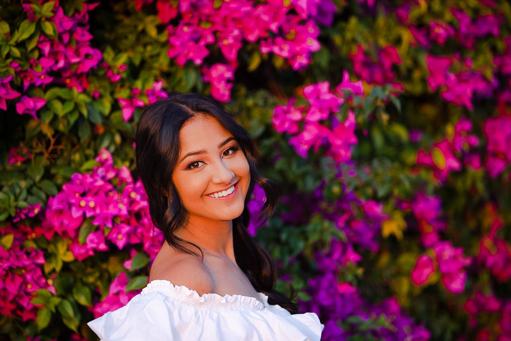 Portrait against vibrant pink bougainvillea flowers and green foliage.