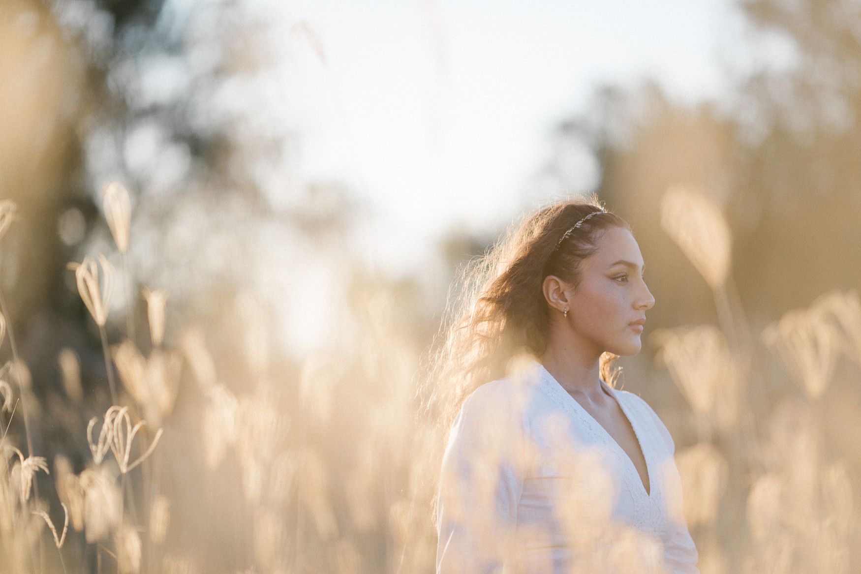 Portrait in white clothing among golden wheat field at sunset.