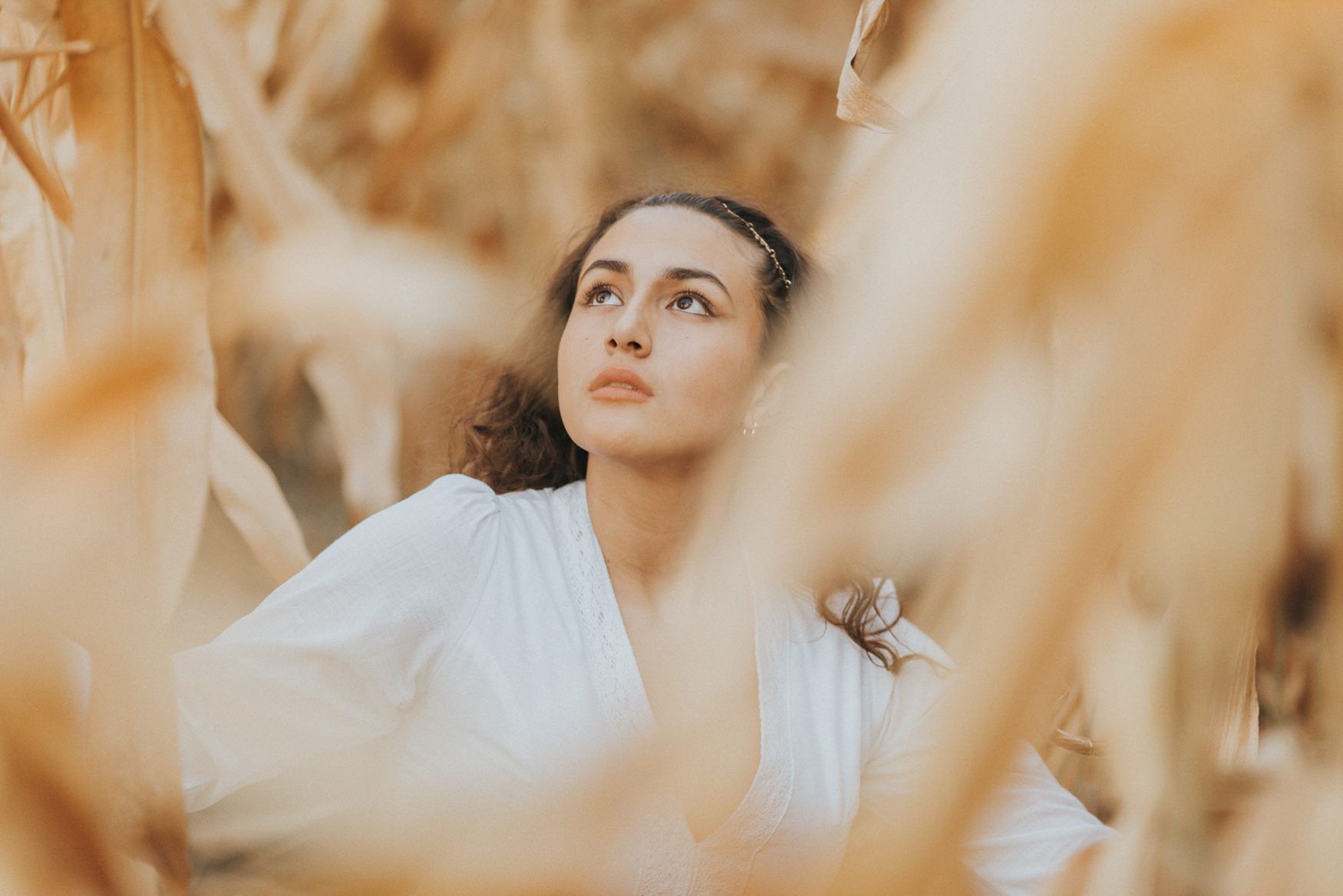Dreamy portrait through dried plants in soft golden light.