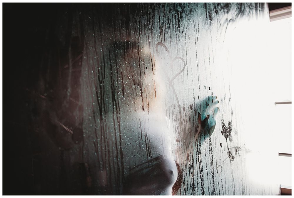 Textured surface with condensation or water droplets creating ethereal pattern in light.
