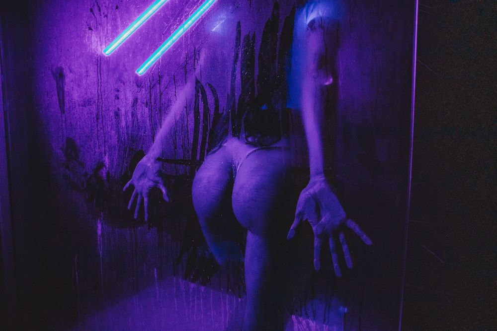 Purple ultraviolet lights create ethereal atmosphere in dark industrial space.