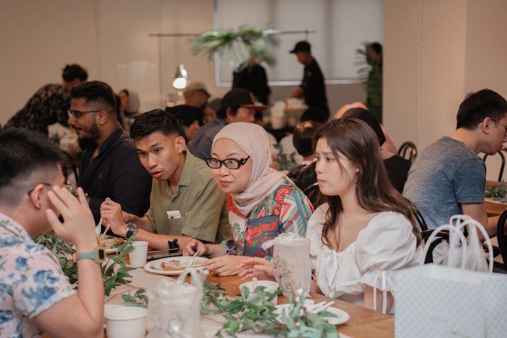 Diverse group of people enjoying a meal at decorated tables in a modern restaurant setting.