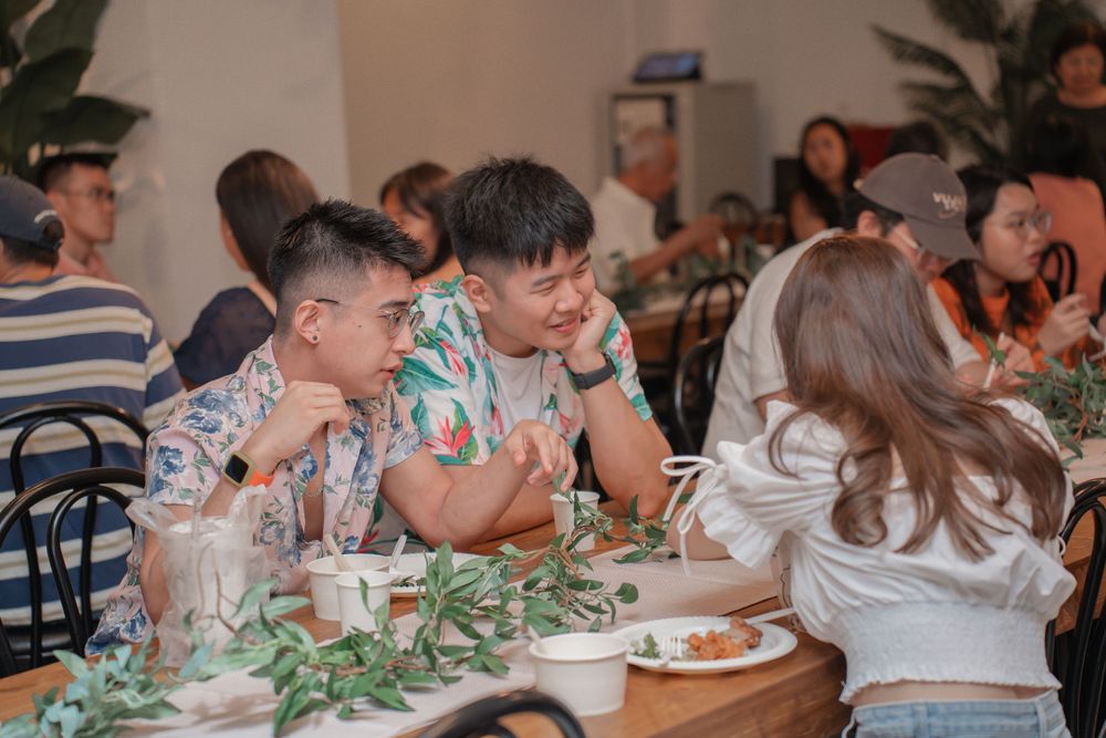 Guests enjoying a meal together at a casual indoor dining event with tropical decor.