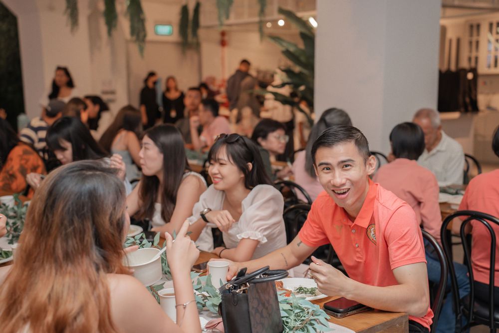 Diners enjoy a social gathering at tables in a restaurant with hanging plants.
