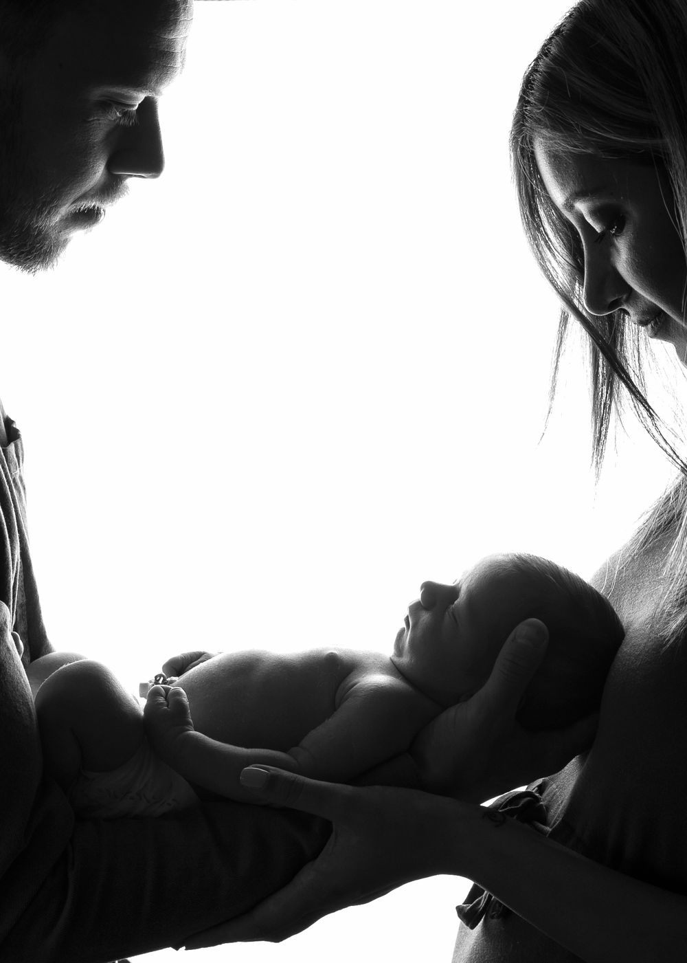 Black and white silhouette of mum and dad holding new born baby