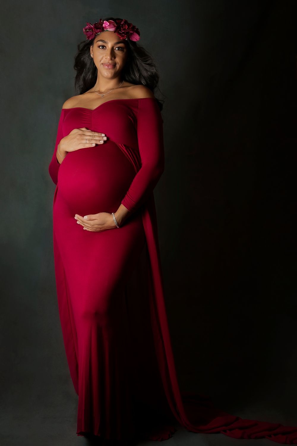 studio maternity shoot.image of pregnant lady standing in long red dress and flower crown
