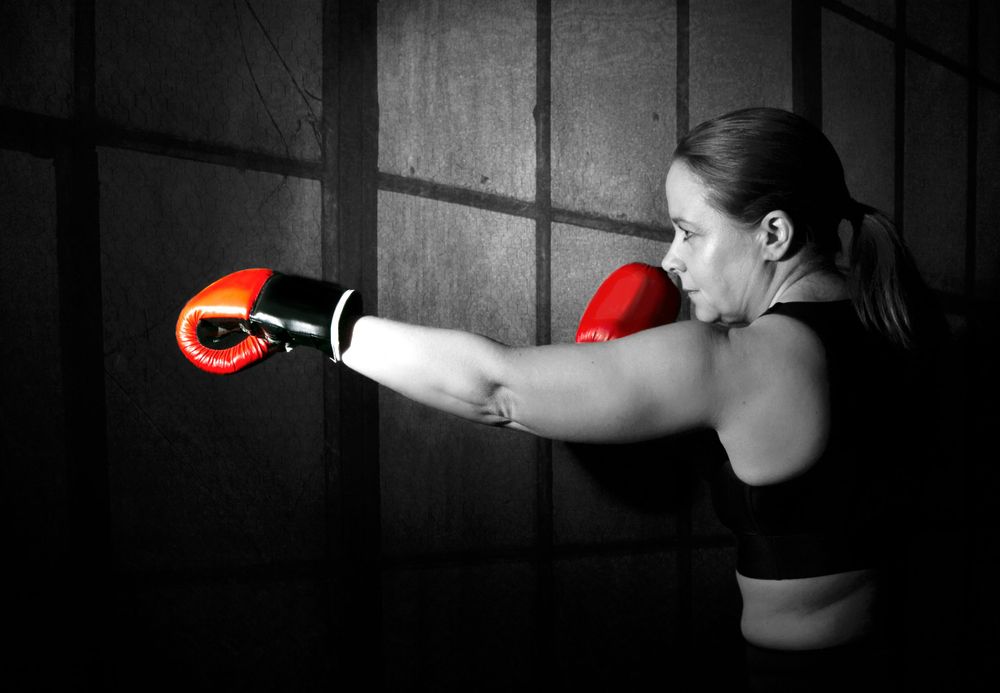 side view black and white image of lady with boxing gloves