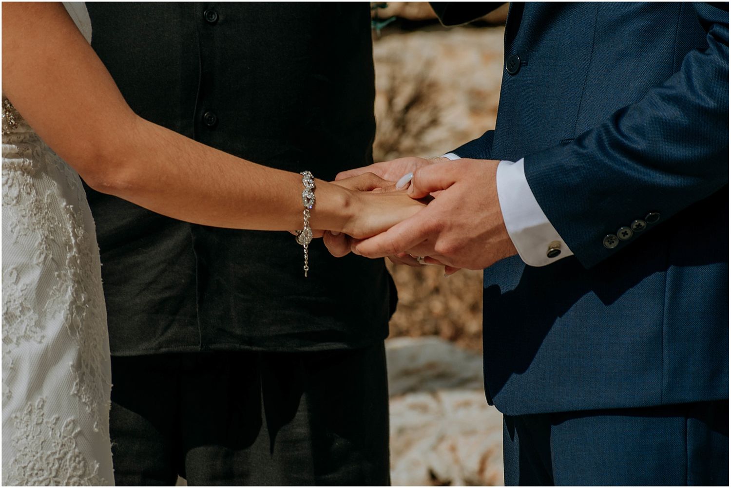 Close-up of hands exchanging rings during an outdoor wedding ceremony.