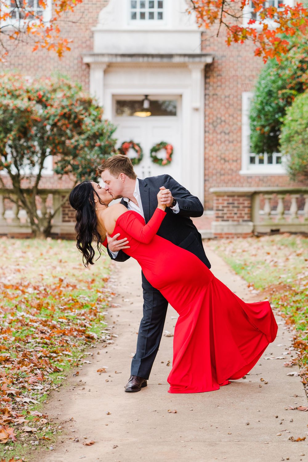 Romantic dip pose on autumn path with red dress flowing dramatically.