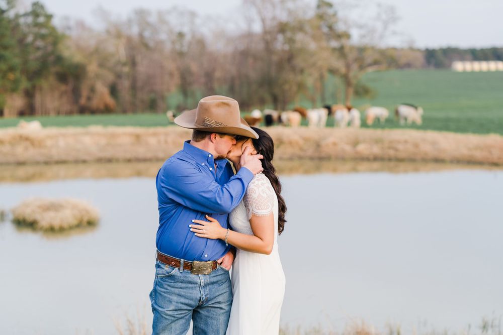 Romantic moment captured by scenic lake with cattle grazing in background.