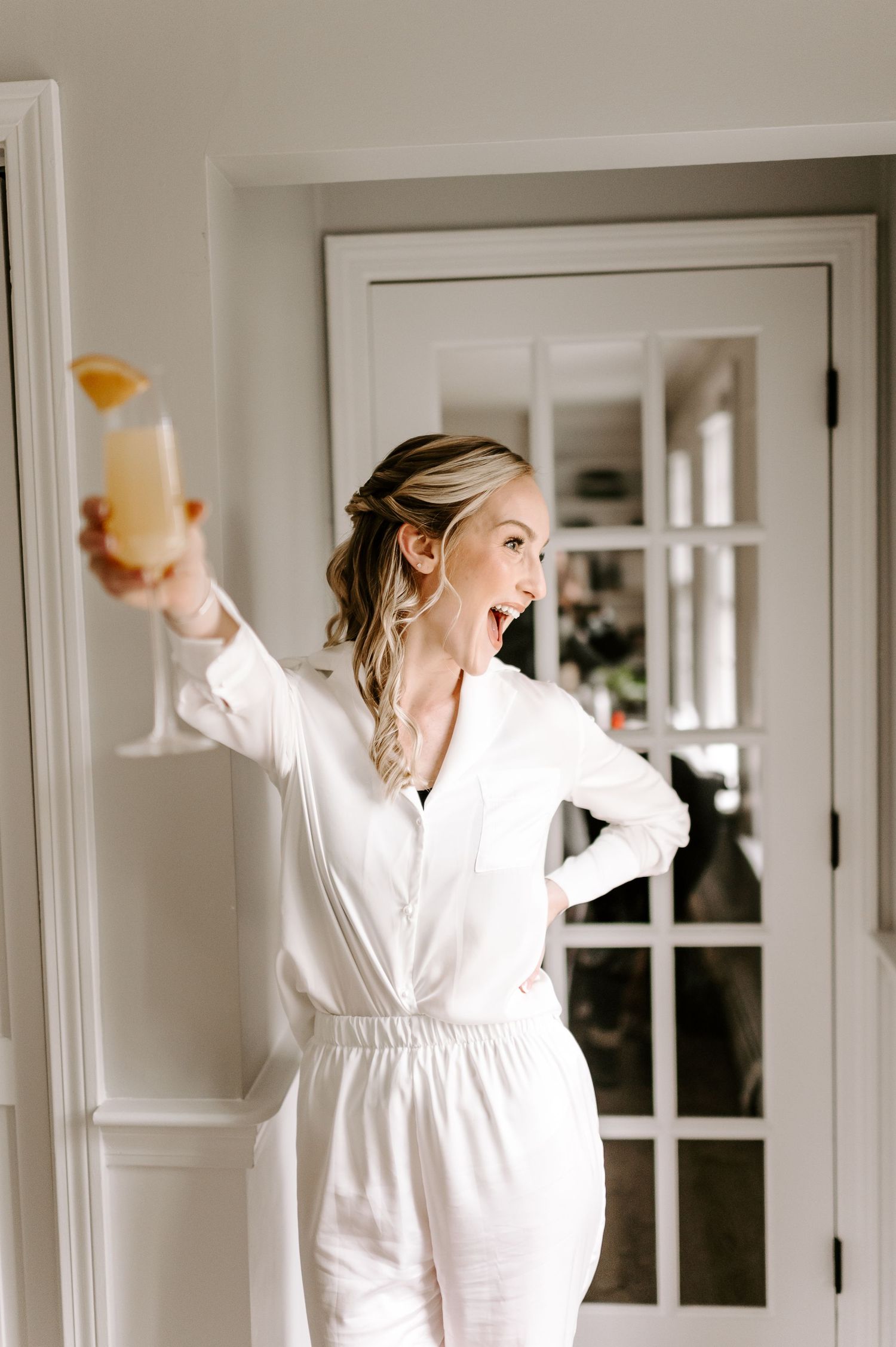 Person in white robe dancing with arms raised in a bright room.
