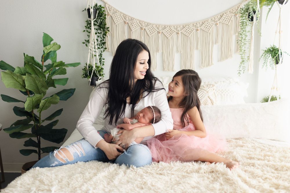 Family moment on cream bedding with macrame wall hanging and plants.