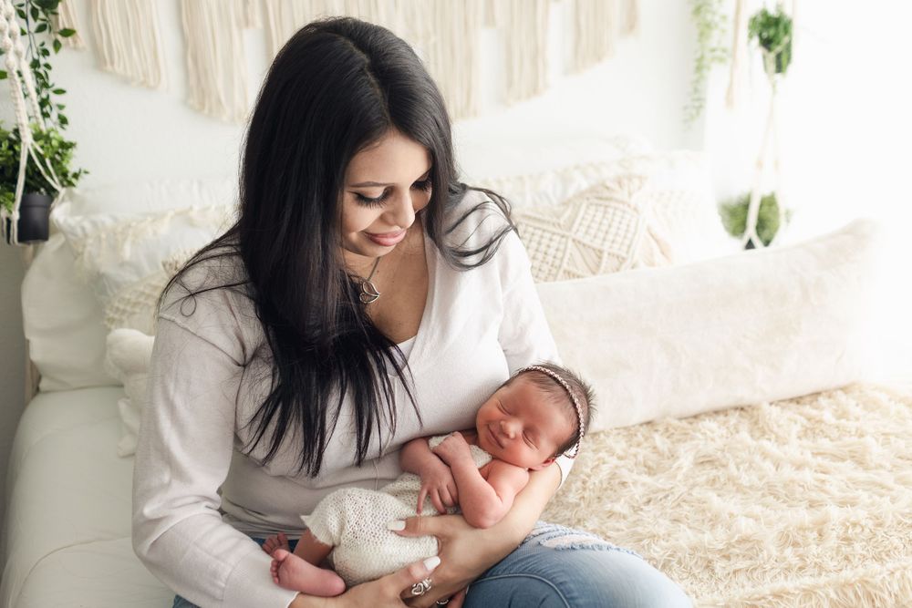 Tender moment with newborn baby wrapped in white against neutral decor.