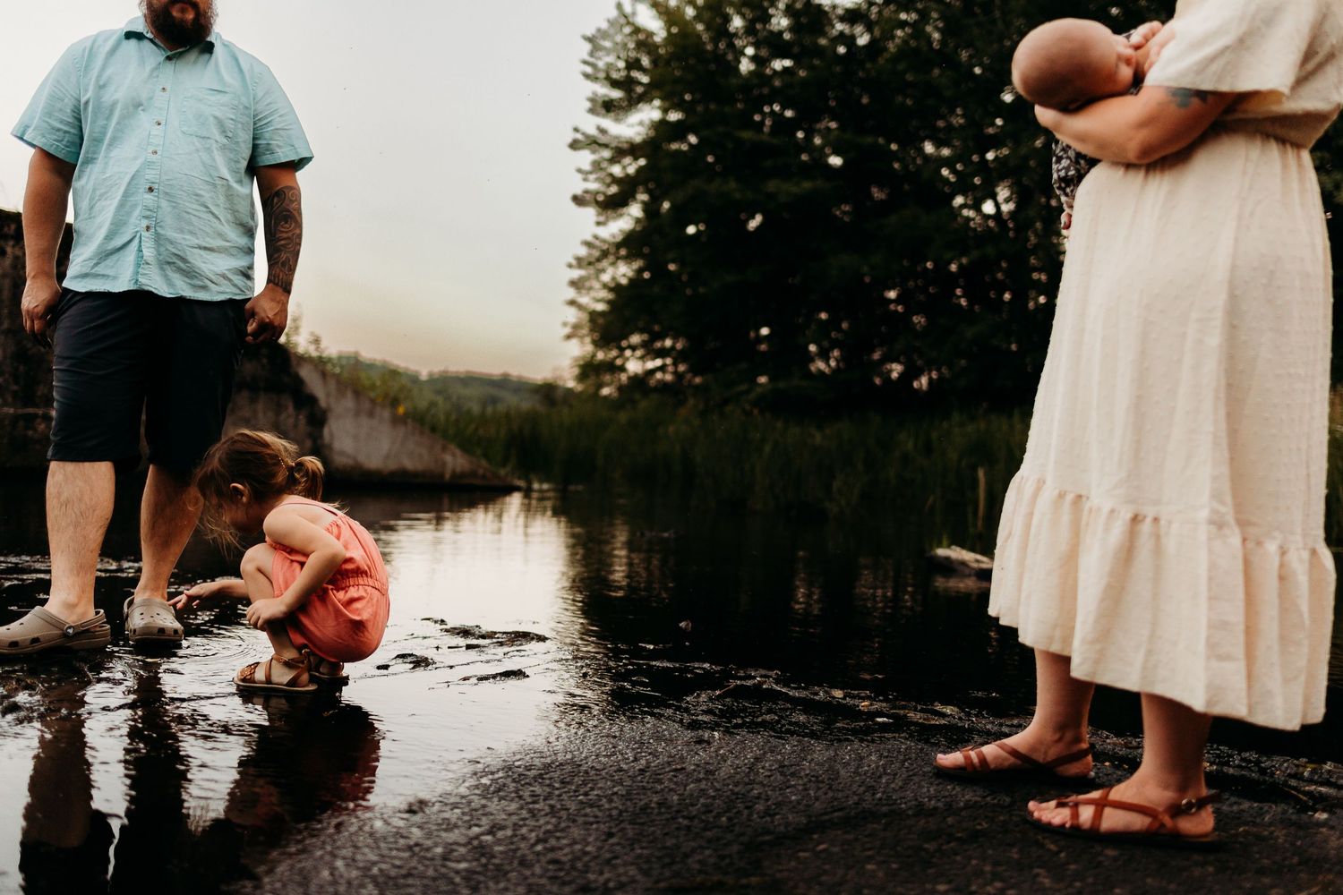 Family exploring the shallow waters of a calm lake during a summer evening.