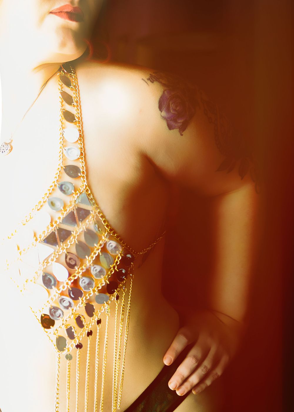 Artistic photo showing decorative gold jewelry against skin in warm lighting.
