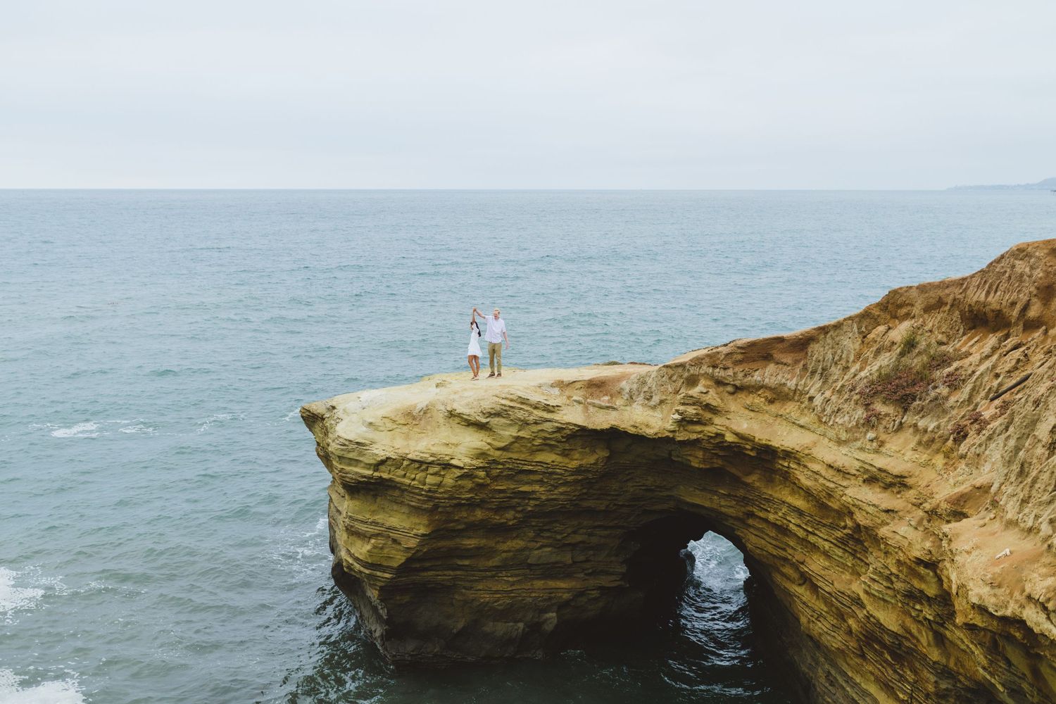 Against the breathtaking backdrop of Sunset Cliffs, a couple takes beautiful engagement proposal photos during sunset.