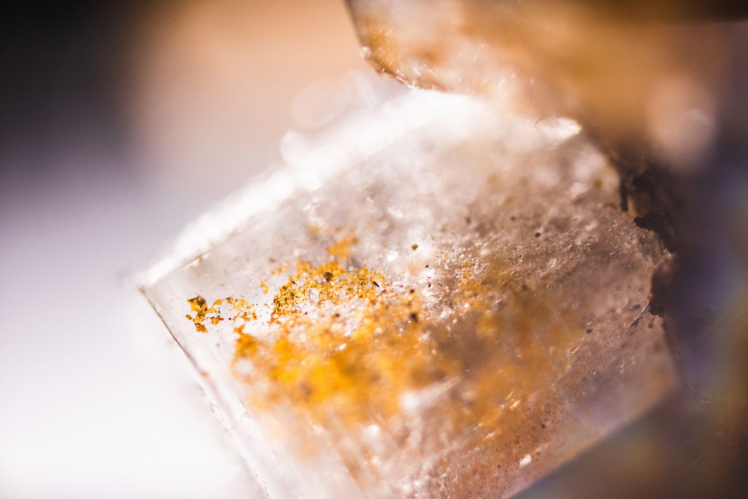 Macro shot of a white crystal with amber-colored inclusions in soft focus.