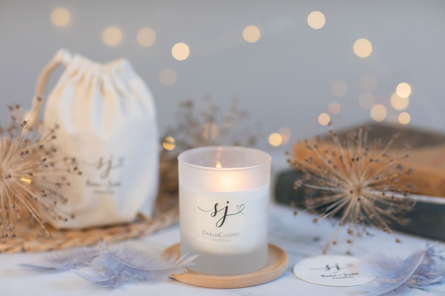 Elegant scented candle in a glass jar with dried flowers and bokeh lights from a product photoshoot.