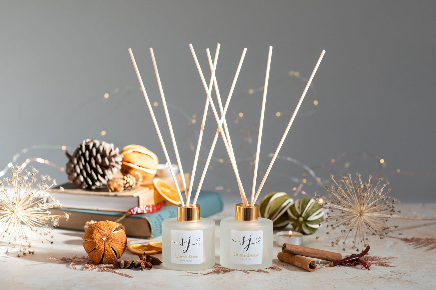 Reed diffusers with wooden sticks and pine cones in a festive holiday setting from a product photoshoot.